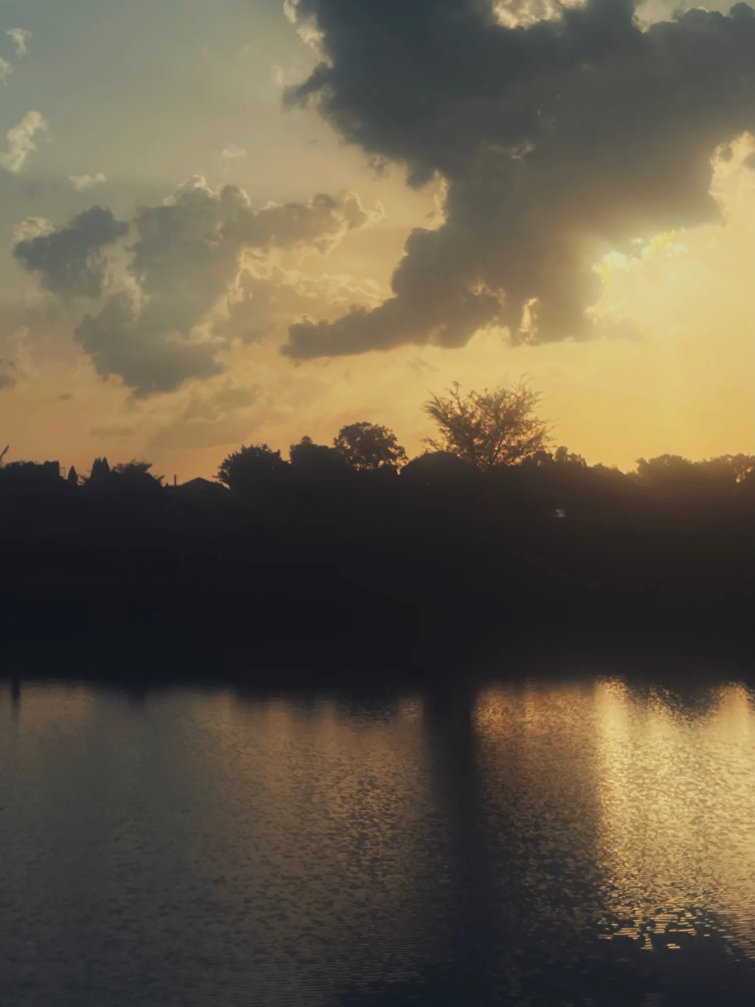 Sunset breaking through clouds over still water